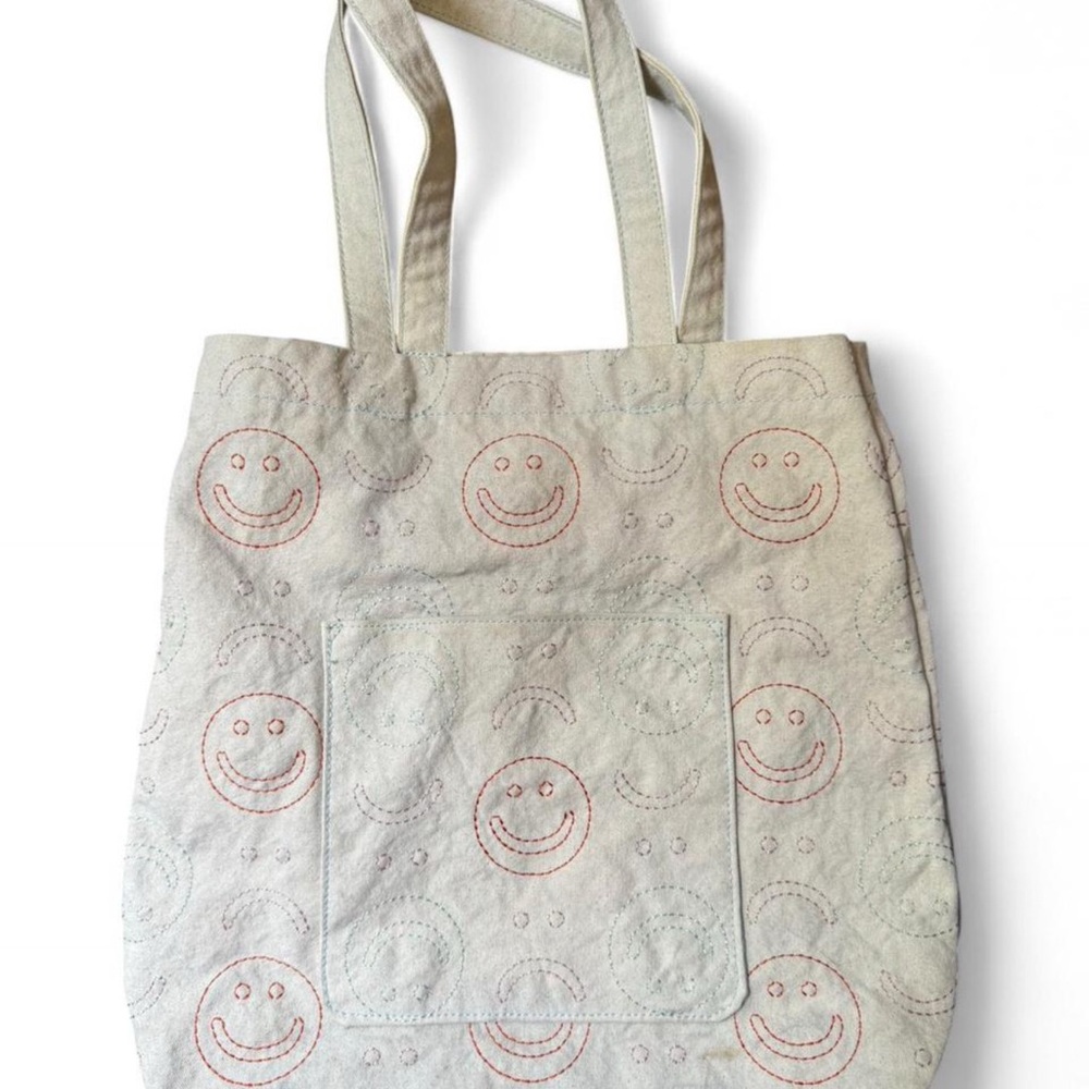 URBAN OUTFITTERS embroidered cute smiley face tote bag with front pocket.